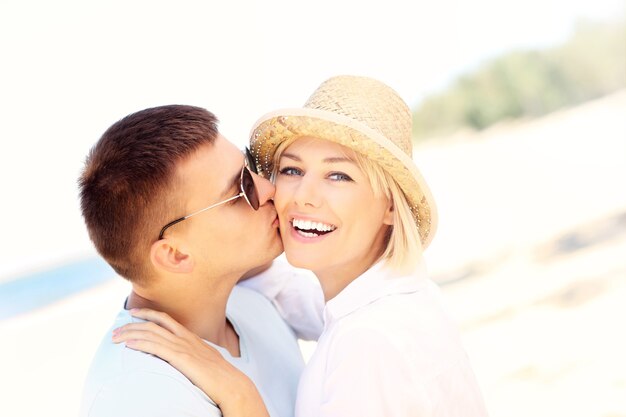 Photo homme embrassant une femme à la plage