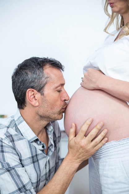 Homme embrassant le ventre d&#39;une femme enceinte à la maison