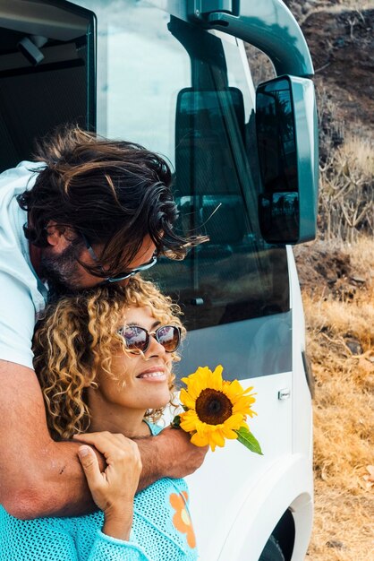 Un homme embrasse une femme et les deux apprécient le style de vie de voyage Un couple heureux étreint et sourit dans la relation contre un camping-car moderne Vacances alternatives sur la route et liberté hors réseau