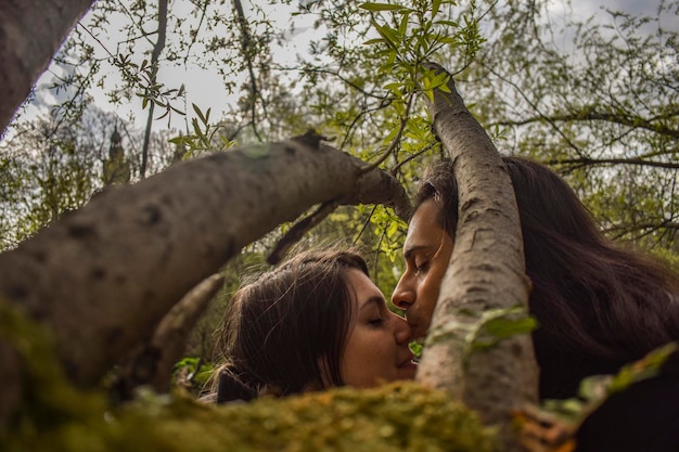 Un homme embrasse une femme par une branche dans la forêt