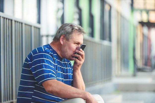 L'homme embrasse joyeusement la communication à distance de l'écran du smartphone avec un être cher par le biais des télécommunications