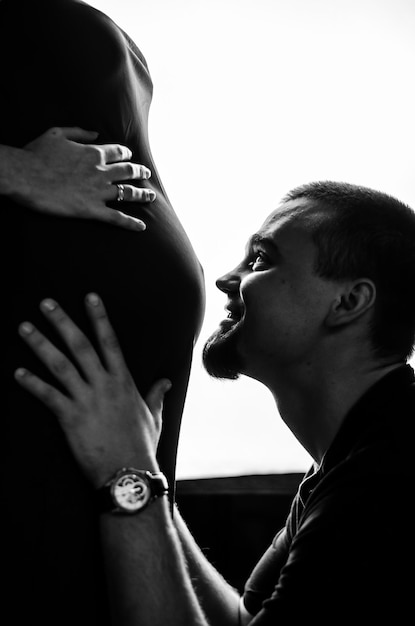 Un homme embrasse sa femme enceinte sur le ventre Photo noir et blanc