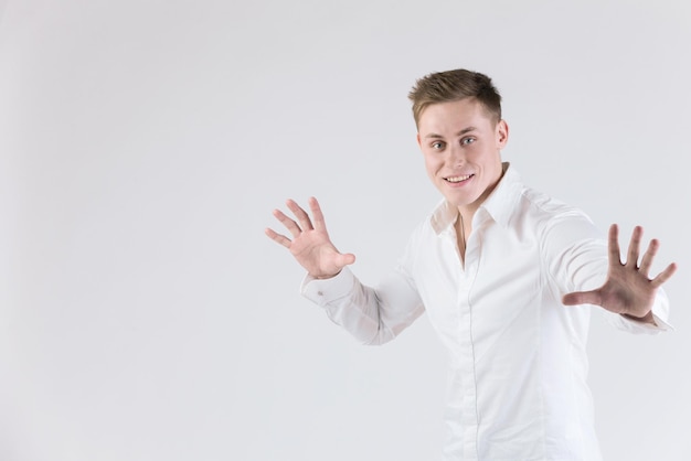 Homme émotionnel avec les bras levés dans une chemise blanche sur fond blanc