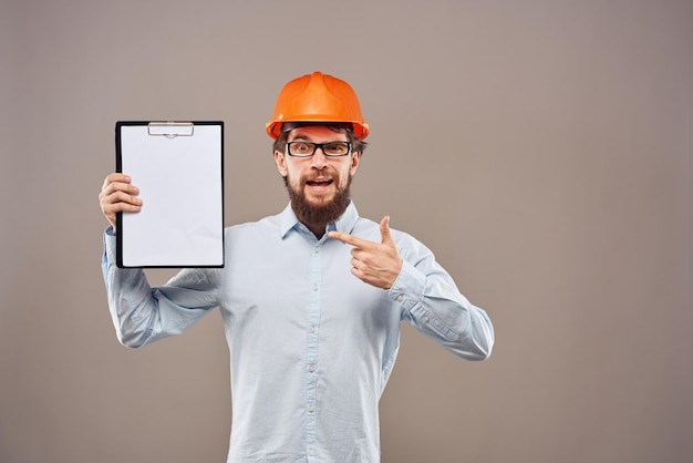 Un homme émotionnel portant un chapeau orange sur des documents de l'industrie Photo de haute qualité