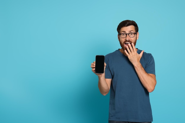 Homme émotionnel avec smartphone sur fond bleu clair Espace pour le texte