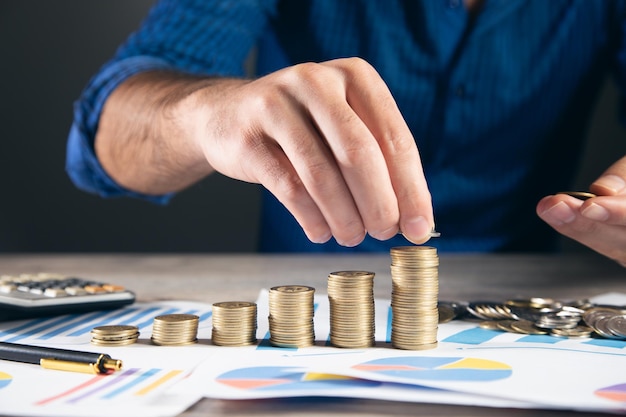 Homme empilant des pièces avec calculatrice sur papier millimétré