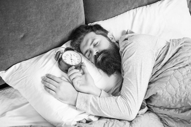 Homme endormi avec réveil étant au lit endormi temps de sommeil