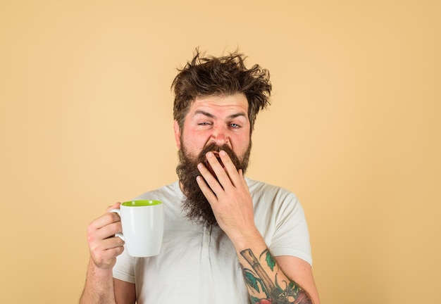 Un homme endormi tient une tasse de café Un homme béant tient une tasse avec un buveur chaud avec une tasse de café frais