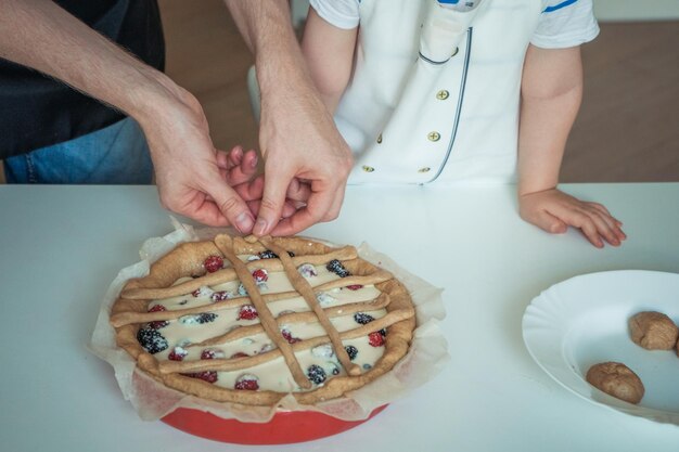 Un homme et un enfant coupent une pizza avec des baies sur le dessus.