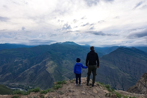 Un homme avec un enfant sur le fond d'une vue sur la montagne depuis l'ancien village de Goor Russie Daghestan 2021