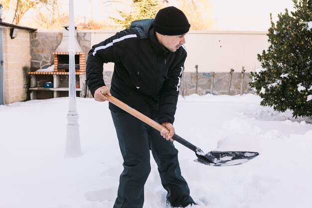 L'homme enlever la neige du jardin de sa maison avec une pelle