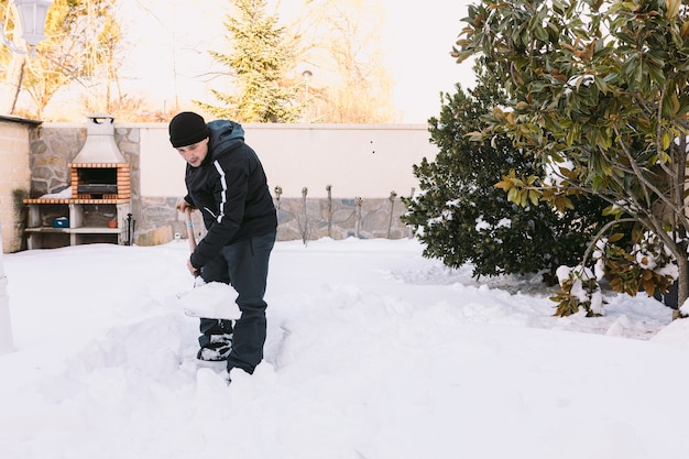 L'homme enlever la neige du jardin de sa maison avec une pelle