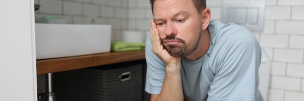 Un homme ennuyé sur un siège de toilette rêve de quelque chose qui répond à un besoin naturel