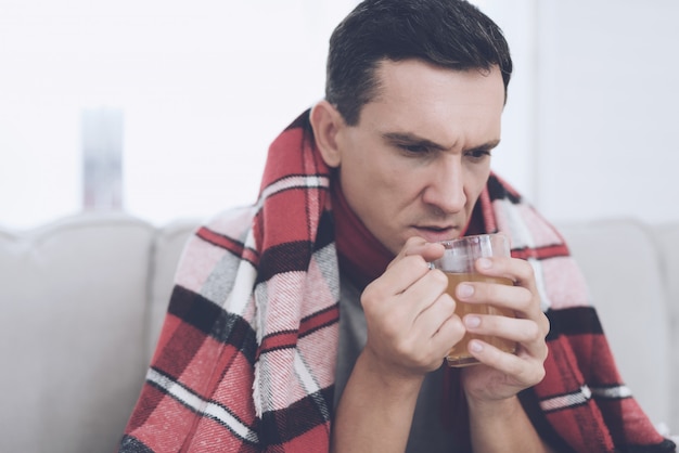 Un homme enrhumé s&#39;assied sur le canapé en éternuant.