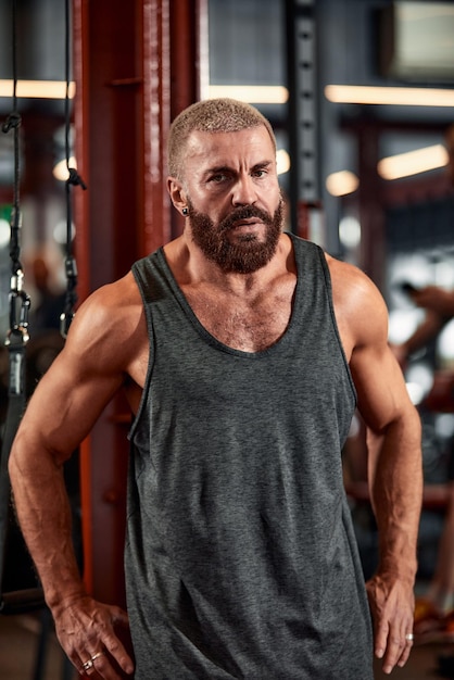 Un homme entraîne ses bras et sa poitrine dans la salle de gym sur le simulateur fait des exercices pour différents groupes musculaires Fintes motivation sport mode de vie santé corps athlétique corps positif Grain de film