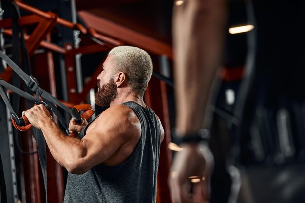 Photo un homme entraîne ses bras et sa poitrine dans la salle de gym sur le simulateur fait des exercices pour différents groupes musculaires fintes motivation sport mode de vie santé corps athlétique corps positif grain de film