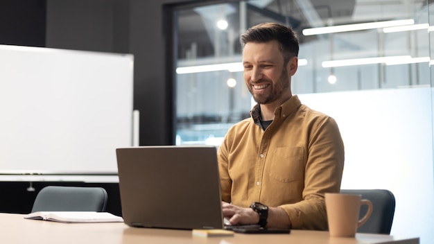 Homme entrepreneur utilisant un ordinateur portable en tapant en ligne sur le panorama du lieu de travail