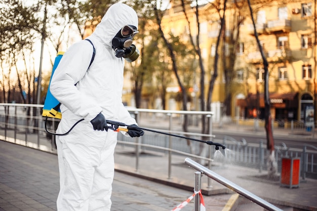 L'homme en équipement de protection désinfectant la ville