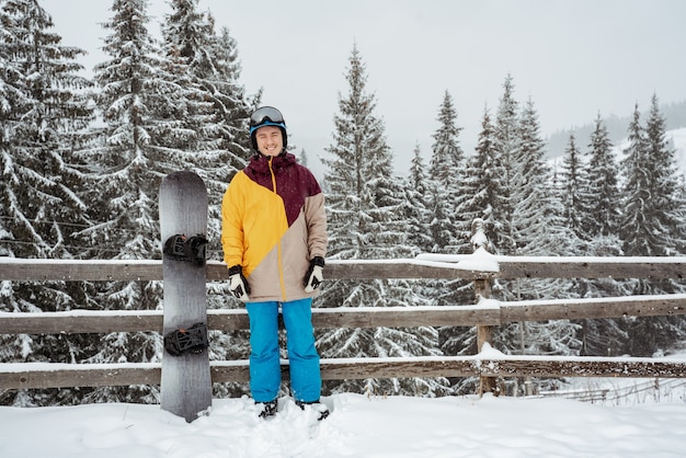 Un homme en équipement de ski, portant des lunettes de sécurité, se dresse contre la montagne et les arbres. Sports et loisirs d'hiver, loisirs de plein air.