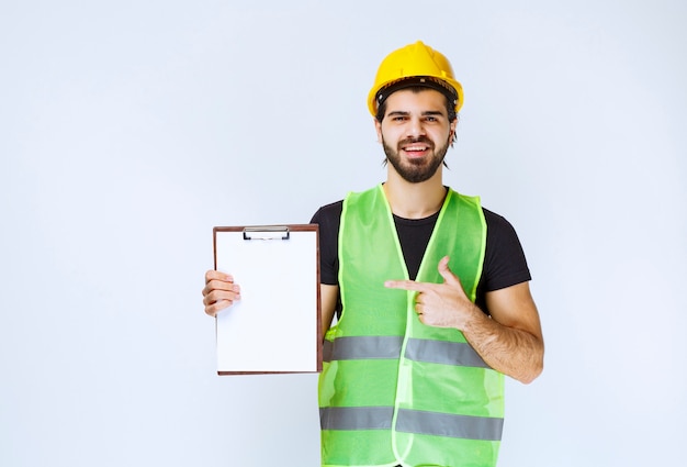 Homme avec équipement tenant le dossier du projet et montrant un signe de satisfaction.