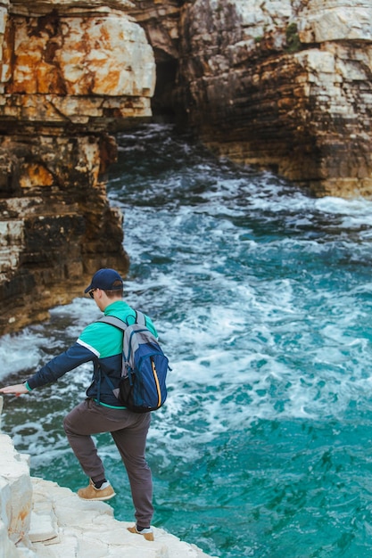 Homme escaladant le bord rocheux profitant du concept de voyage avec vue sur le paysage marin