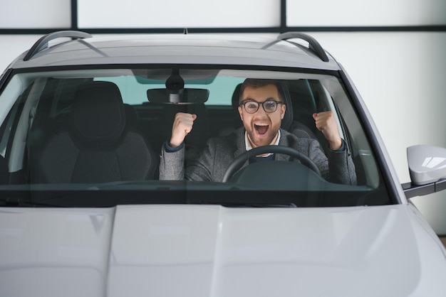 Homme d'esprit client acheteur masculin client en costume choisir auto pour aller regarder de côté vouloir acheter une nouvelle automobile dans la salle d'exposition de voitures salon de véhicules concessionnaire magasin salon de l'automobile concept de vente intérieur