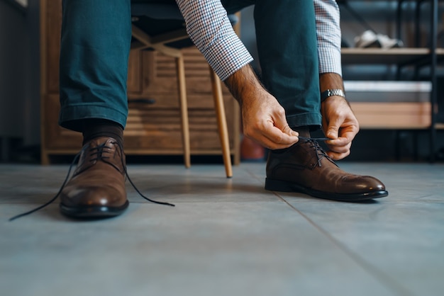 L'homme essaie des chaussures réparées, un service de réparation de chaussures. Compétence d'artisan, atelier de cordonnerie, maître travaille avec des bottes, cordonnier