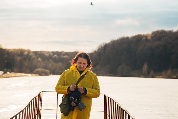 Photo un homme essaie de retirer le masque sur le fond du paysage naturel avec rivière et forêt problèmes environnementaux