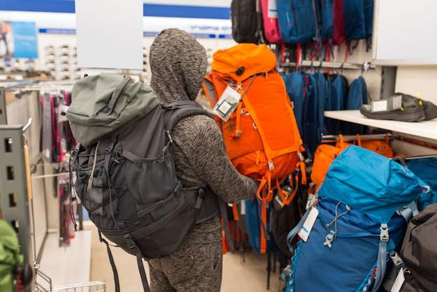 Homme essayant un grand sac à dos de randonnée pour voyager, dans un centre commercial