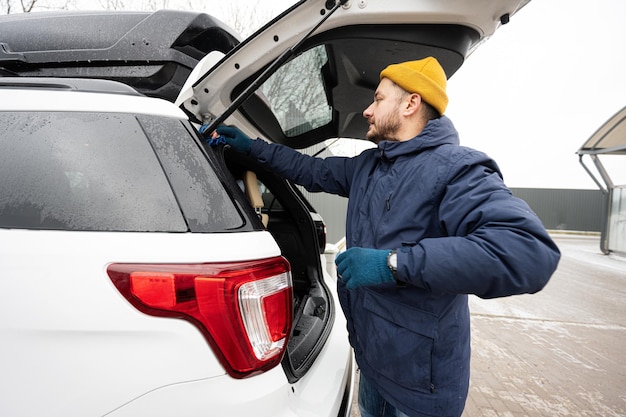 L'homme essuie le coffre d'une voiture SUV américaine avec un chiffon en microfibre après le lavage par temps froid