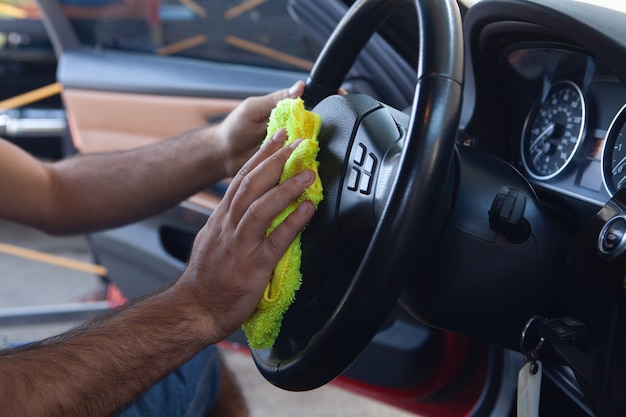 Un homme essuie l'intérieur d'une voiture avec un chiffon