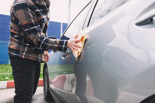 L'homme essuyant sa voiture après s'être lavé dans le lave-auto