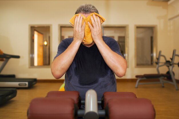 Homme essuyant le visage avec une serviette après l&#39;entraînement