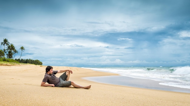 L'homme est allongé sur une plage tropicale