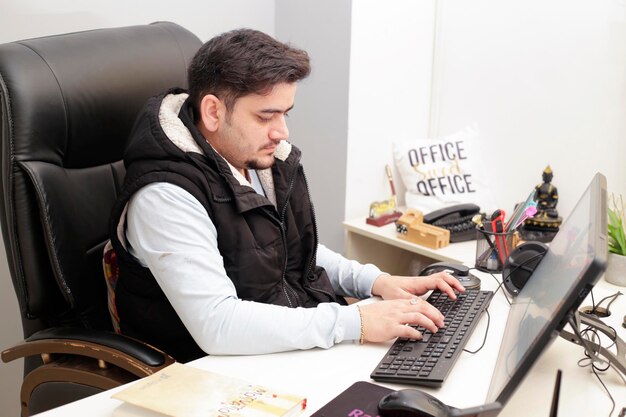 Un homme est assis à un bureau devant une pancarte indiquant office office.