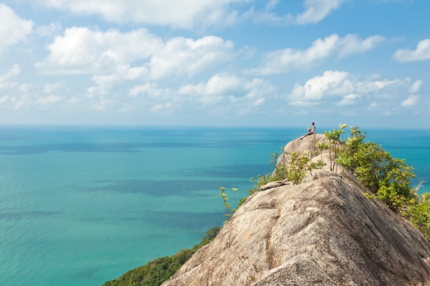 Un homme est assis sur une colline avec une vue imprenable sur la mer