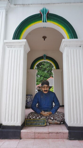 Photo un homme est assis dans une salle de méditation avec une arche verte et jaune au-dessus de lui.