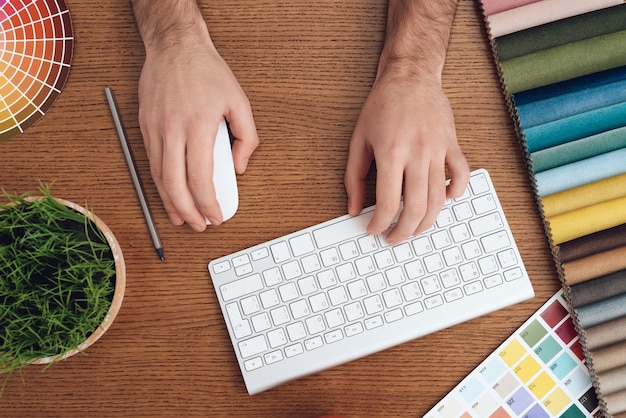 L'homme est assis devant l'ordinateur portable et travaille dans un bureau de création.