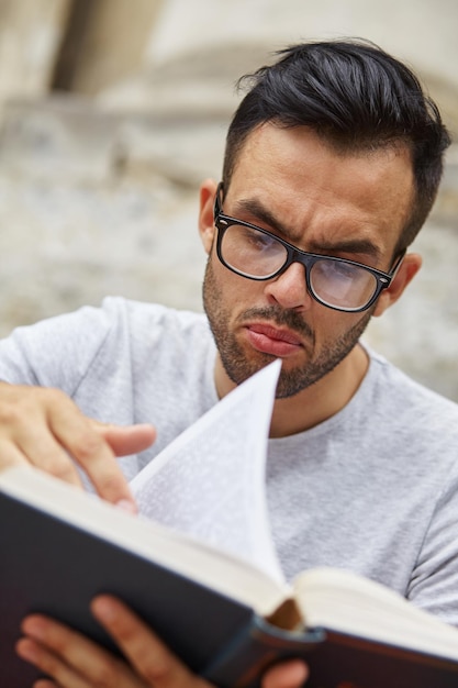 Un homme est assis et lit un livre avec émotion