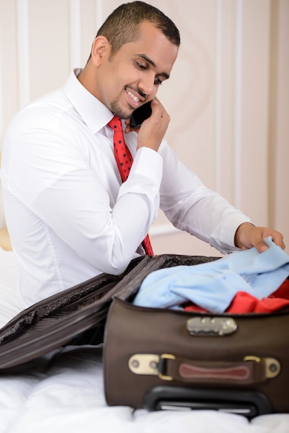 Un homme est assis et parle au téléphone et ramasse une valise.