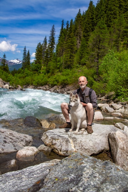 Un homme est assis près de la rivière avec son chien