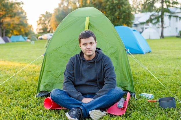 L'homme est assis près de la tente dans la zone de camping