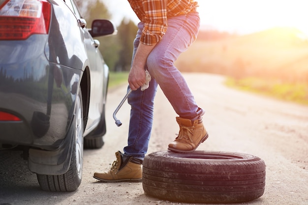 L'homme est assis sur la route près de la voiture dans la nature