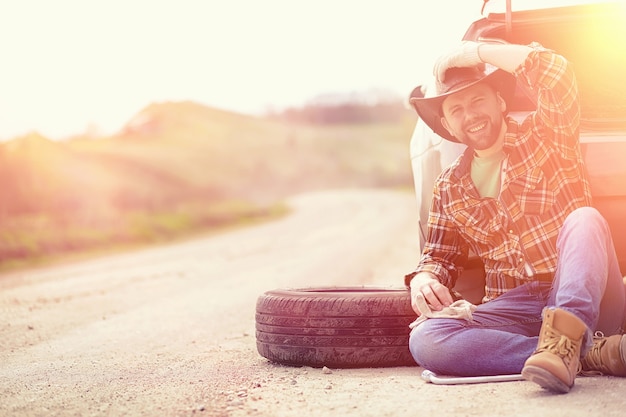 Photo l'homme est assis sur la route près de la voiture dans la nature