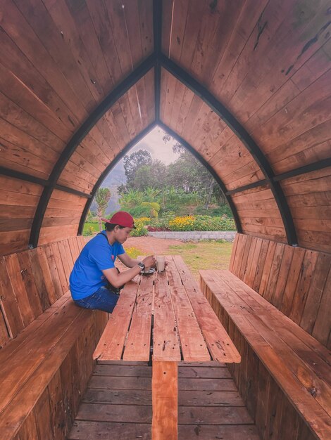 Un homme est assis sous un pavillon de bois.