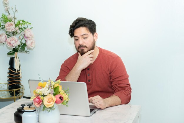 Un homme est assis à une table avec un ordinateur portable et des fleurs dessus