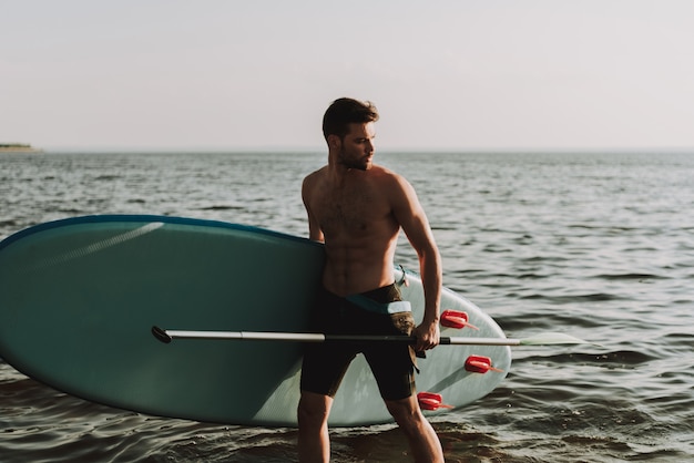 L&#39;homme est debout sur la plage avec Surf.