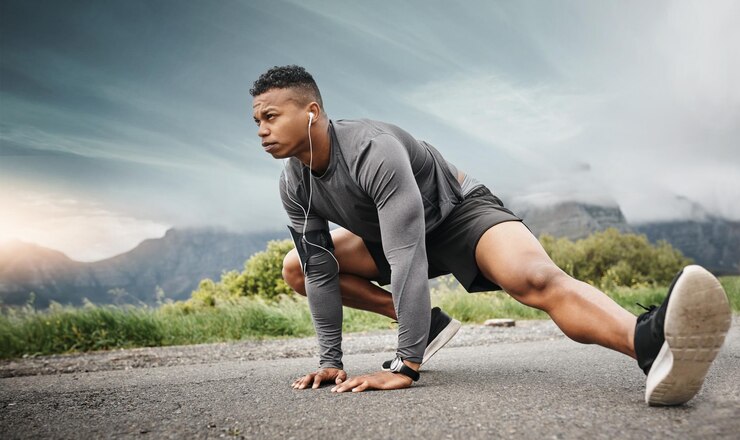 Photo homme étirant les jambes et la musique avant l'entraînement fitness et entraînement sur la route en plein air homme athlète casque et exercice pour le bien-être de la santé et de la flexibilité avec l'endurance ou l'équilibre dans la nature