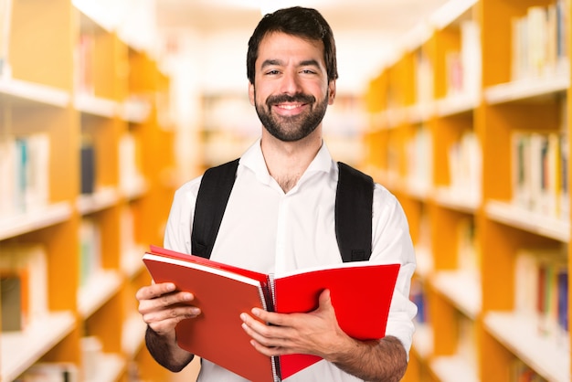 Homme étudiant avec des cahiers sur une bibliothèque défocalisée