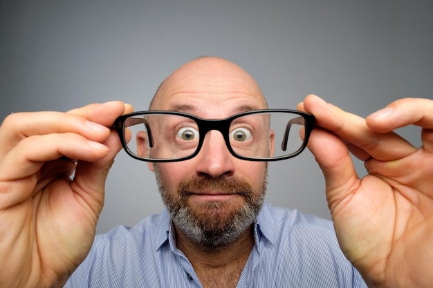 Homme européen drôle regardant à travers des lunettes Avoir des problèmes de vue